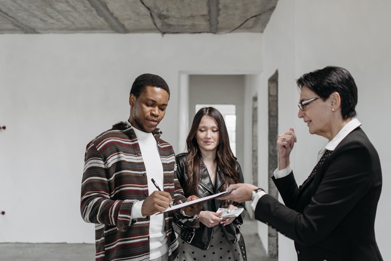 Mastering the First Impression: Your intriguing post title goes here A diverse couple signing documents with a realtor in a new home setting.